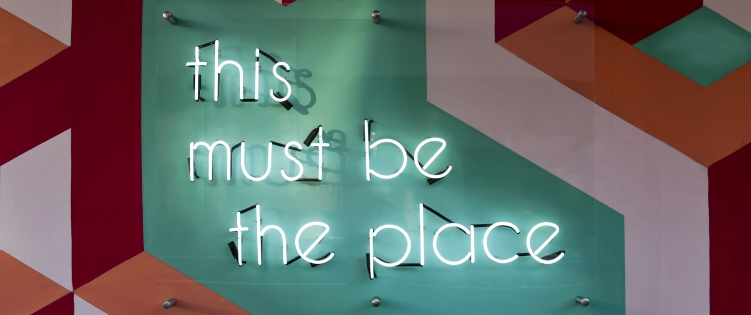 An image with a neon sign that says this must be the place
